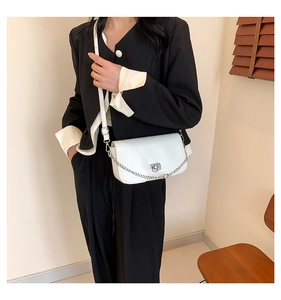Sac bandoulière blanc chic avec chaîne argentée porté par un mannequin en costume moderne