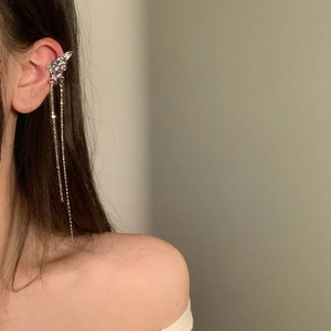 Detail showing a silver butterfly ear bone clip with long tassel chains on a model's ear