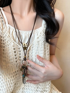 Detail of ethnic multilayer necklace with leather cord, feather, and gem pendants