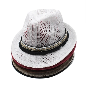 Detailed view of stacked hollow knit fedora hats featuring decorative tassel bands