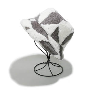 Détail du motif géométrique gris et blanc en peluche sur un chapeau bob d'hiver