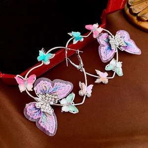 Close-up of colorful embroidered butterfly hoop earrings with sparkling rhinestones