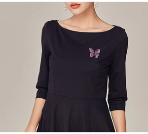 Detail of a purple crystal butterfly brooch pinned on a black off-the-shoulder dress