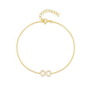 Macro detail of gold infinity charm bracelet featuring sparkling white zircon stones