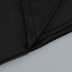 Macro shot showing the texture and fold of black high-density fabric for elegant evening gowns