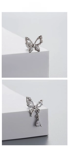 Macro shot of butterfly stud earrings with sparkling white zircons and teardrop pendant
