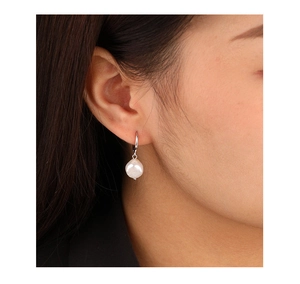 Close-up of a natural freshwater pearl earring with silver hook on a model ear