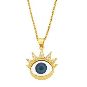 Goldene Evil Eye Halskette mit funkelnden Kristallen und tiefblauem Auge auf weißem Hintergrund