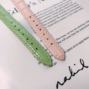 Detailed view of pink and green leather watch straps with luxury crocodile texture