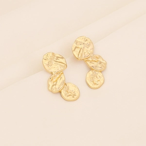 Minimalist gold geometric irregular earrings with hammered texture on beige fabric