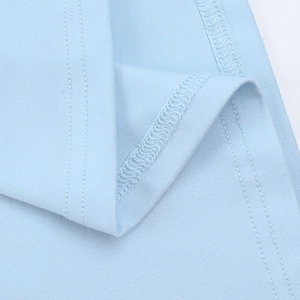 Dettaglio dell'abito in maglia azzurro che mostra doppie cuciture e rifiniture overlock