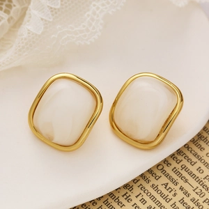 Vue macro de boucles d'oreilles carrées plaquées or avec résine crème et dentelle