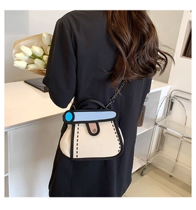 Detail of 2D cartoon style canvas bag with blue flap and elegant silver chain strap