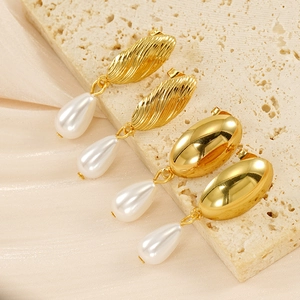 Dettaglio di orecchini vintage con perle dorate su pietra e seta champagne