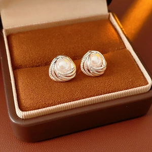 Detailed macro of silver vortex pearl earring resting in a premium brown velvet jewelry box