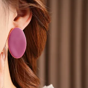 Orecchini ovali bordeaux scuro con bordo dorato indossati da una modella
