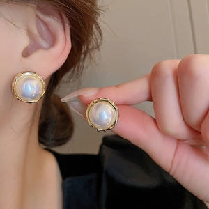 Gros plan détaillé des boucles d'oreilles perles papillon avec bordure dorée et zircon