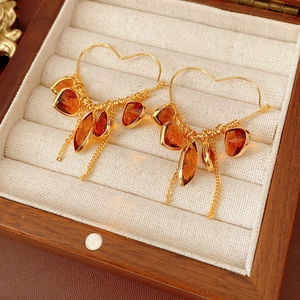 Detail of 18K gold-plated heart hoop earrings with amber glass stones in a jewelry box