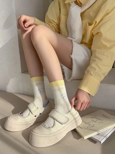 Detail view of cute cream crew socks with bear pattern and yellow ribbed cuffs