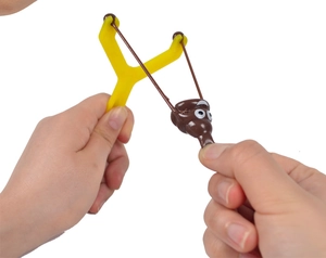 Close-up of hands stretching a creative brown poop slingshot toy with a yellow handle