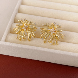 Détail macro de boucles d'oreilles fleurs dorées avec zircons sur un plateau à bijoux