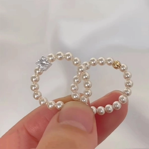 Elegant round pearl chain rings with square zircon and golden bead on white silk fabric