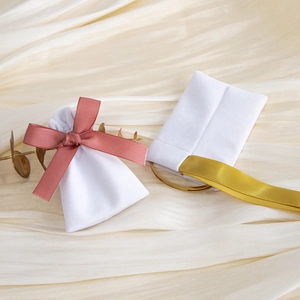 White velvet jewelry pouches with pink and gold silk ribbons and metal rings