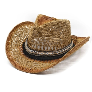 Détail d'un chapeau de cowboy en paille tissée avec ruban ethnique et franges noires