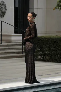 Détail d'une robe longue en dentelle noire transparente portée au bord d'une piscine