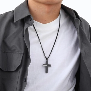 Close-up of black stainless steel cracked cross pendant necklace worn by male model