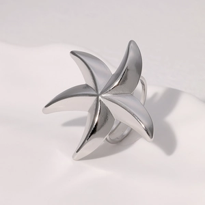 Macro shot of silver starfish ring with glossy finish on a minimalist wavy texture