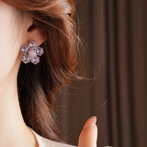 Détail d'une boucle d'oreille fleur rose et violette avec cristaux sur le mannequin