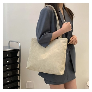 Model wearing a large cream corduroy tote bag for a minimalist stylish shoulder look