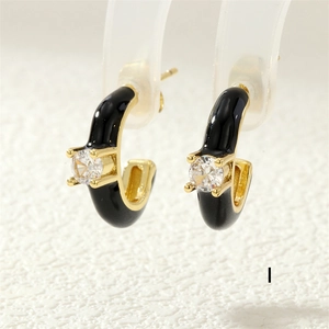 Macro shot of black enamel C-shaped gold earring with a clear inlaid zircon stone