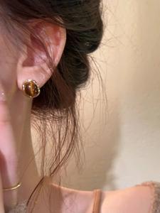 Detail of 18k gold plated tiger eye stone stud earring on model with vintage aesthetic