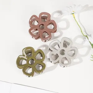 Close-up of three floral shark clips in olive green, pink, and grey with matte finish