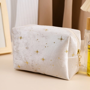 Close-up of silver-grey velvet makeup bag featuring gold star embroidery and metal zipper