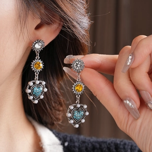 Macro detail of vintage floral pearl earrings with blue heart crystal and diamonds