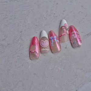 Detail of pink gradient press-on nails with 3D bows, pearls, and glitter finish