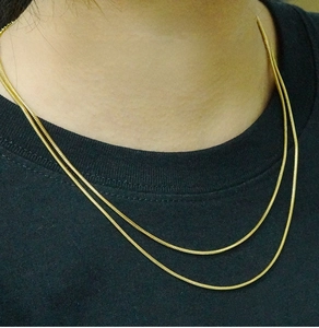 Detail einer 18K vergoldeten, zweilagigen Schlangenkette aus Edelstahl am Hals des Models