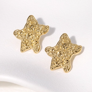 Macro shot of gold star stud earrings featuring unique hammered metal texture detail