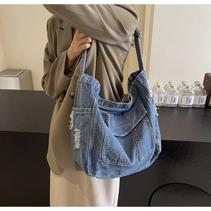 Détail du grand sac cabas en jean bleu foncé avec bords usés et coutures apparentes