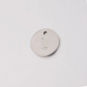 Macro shot of silver mirror polished stainless steel round tag with engraved letter L