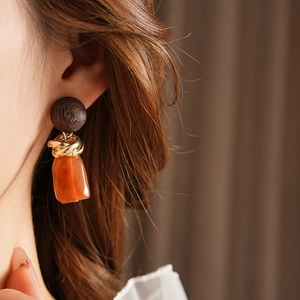 Close-up of vintage geometric wood and resin drop earrings on model in warm brown tones