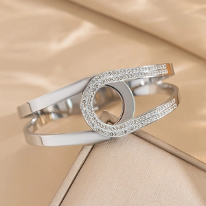 Bracelet jonc ouvert en acier titane argenté avec strass sur boîte à bijoux dorée