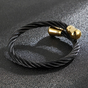 Macro detail of black twisted cable cuff bracelet with polished gold bullet ends