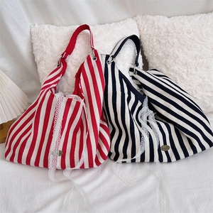 Détail d'un sac en toile avec rayures verticales, bordure en dentelle et emblème en métal