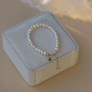 Elegant emerald pearl bracelet with gold adjustable chain on velvet jewelry display