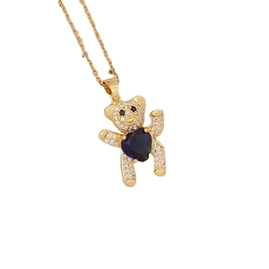 Golden bear necklace with blue heart gemstone and sparkling zircon stones on white background