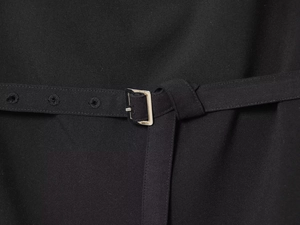 Detailed macro view of black twill fabric belt featuring a polished silver metal buckle